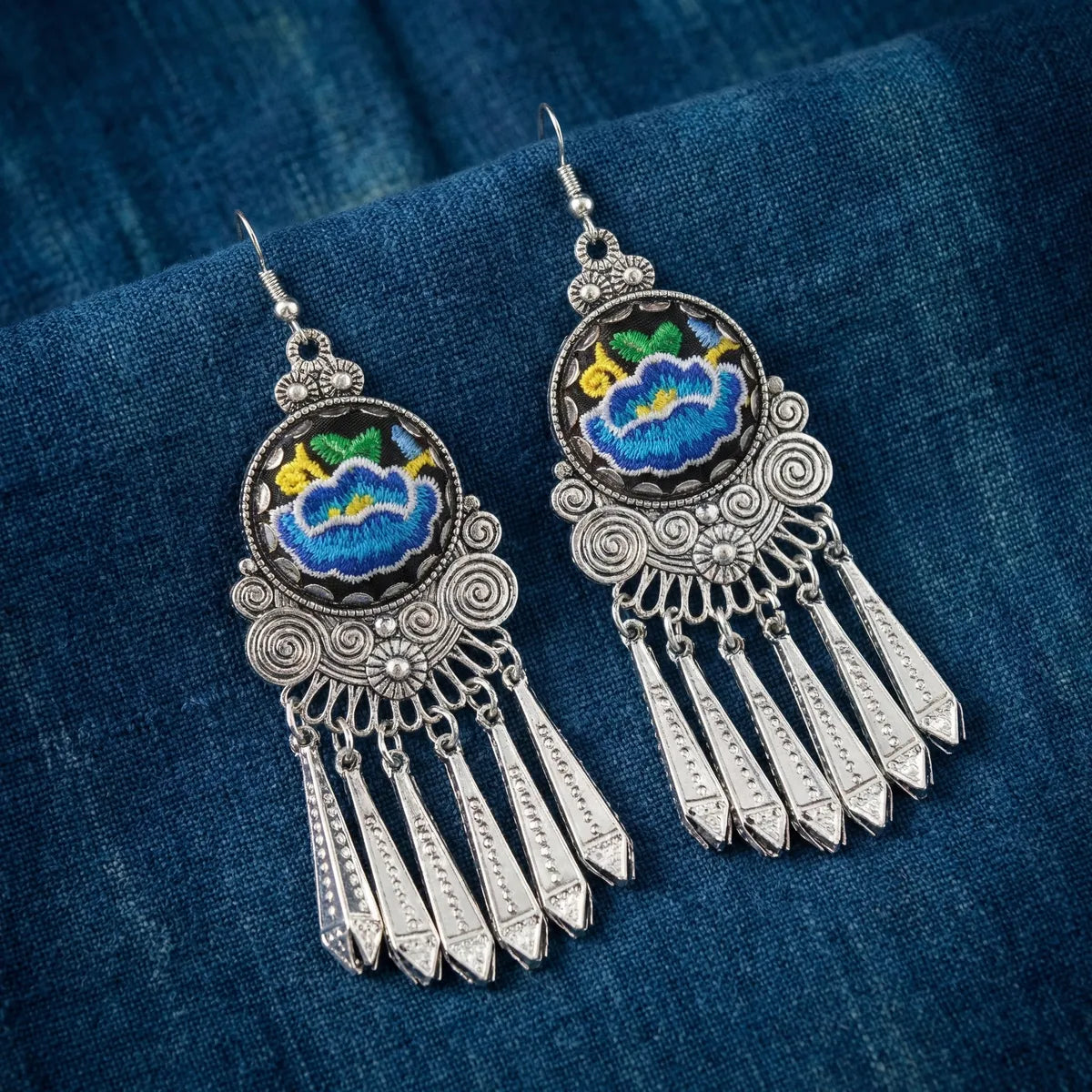 Miao Silver earrings with intricate designs on a blue fabric background