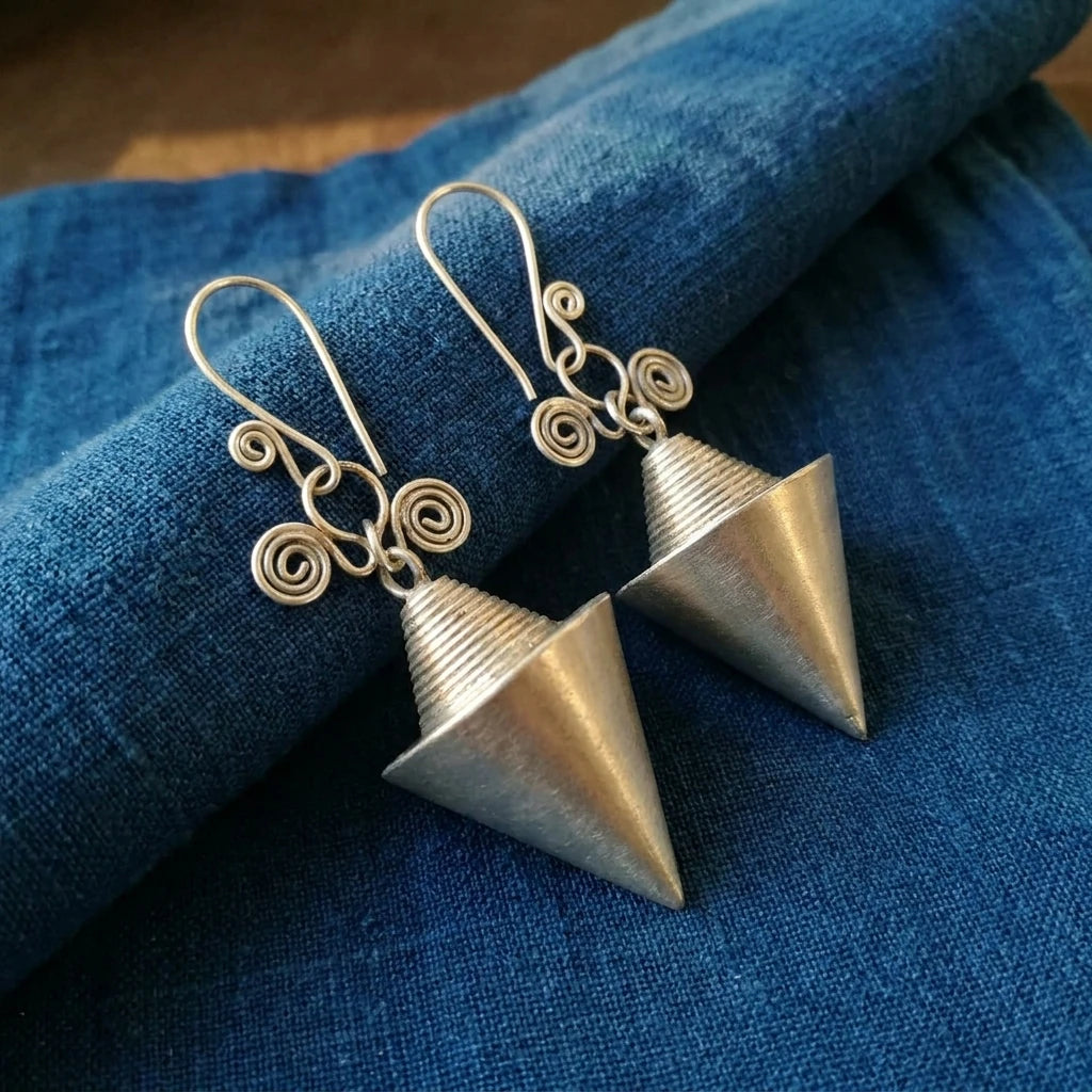 Miao Silver Hollow Cone Earrings displayed on indigo textile