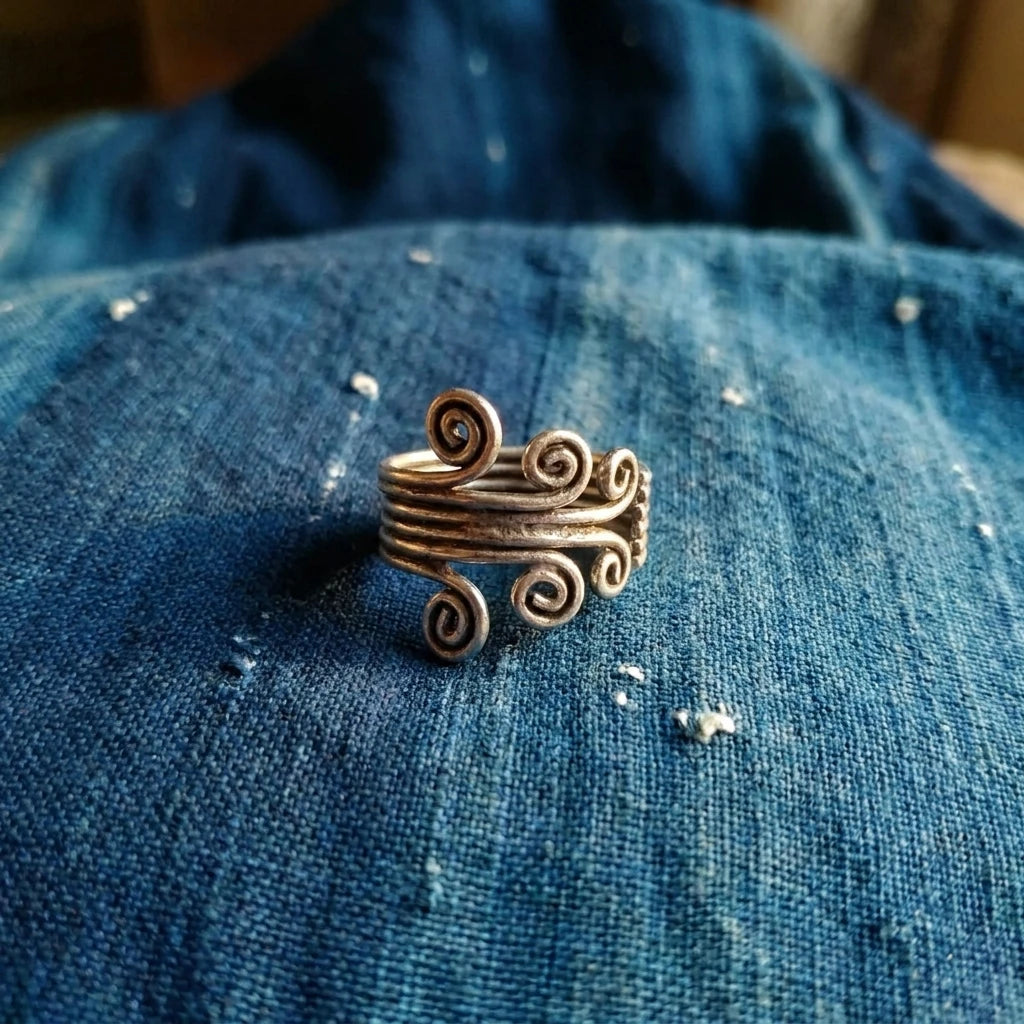 Miao Silver Tall Spiral Adjustable Ring displayed on indigo textile