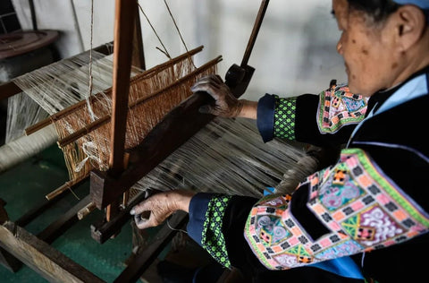 Miao artisan weaving colorful textile on a traditional loom