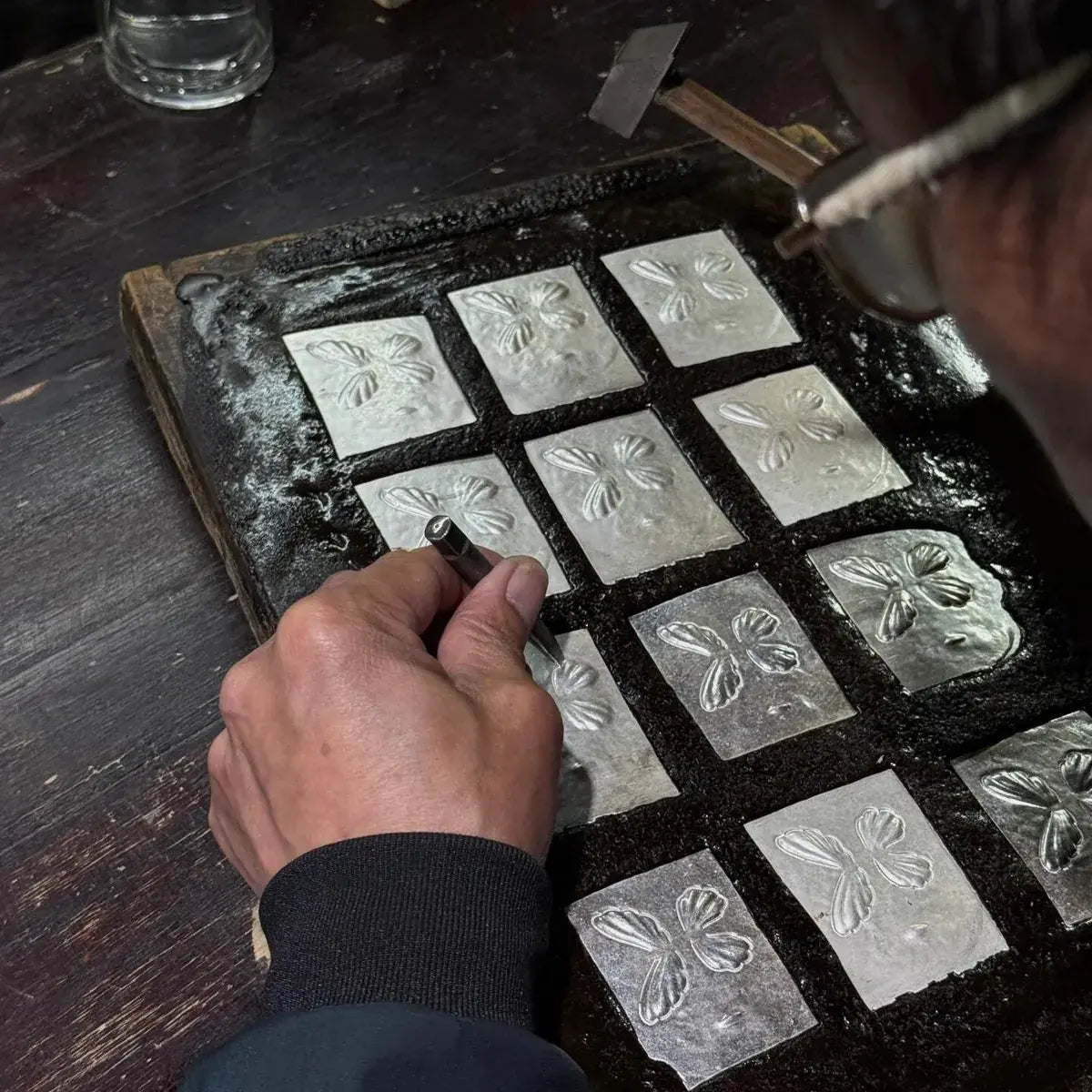 Traditional Miao master silversmith hand-hammering and chasing silver alloy ornaments