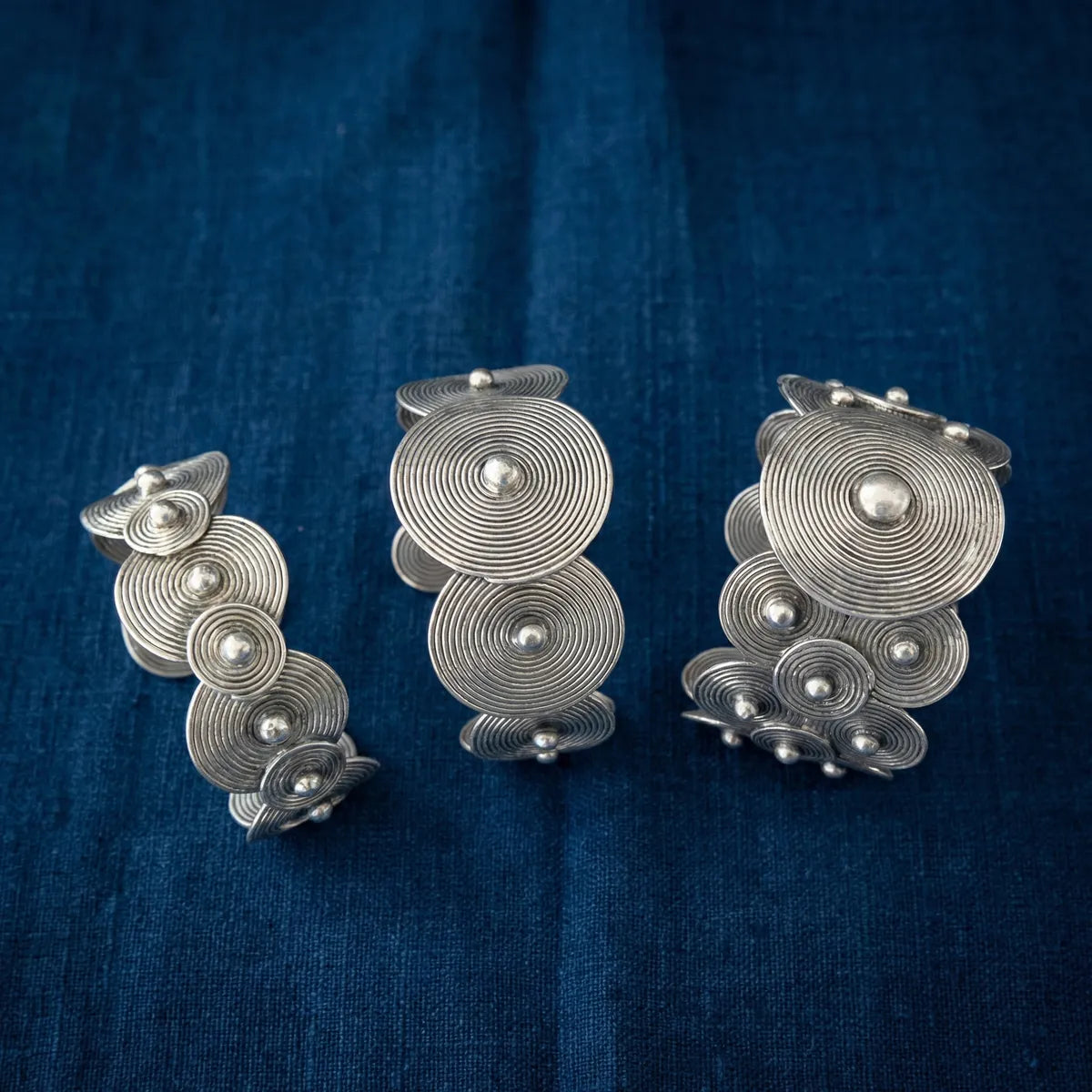 Set of Miao silver circular earrings on a blue fabric background