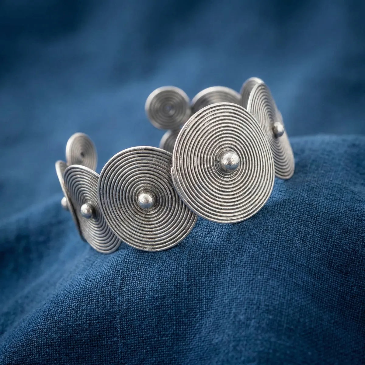 Miao Silver bracelet with circular design on a blue fabric background