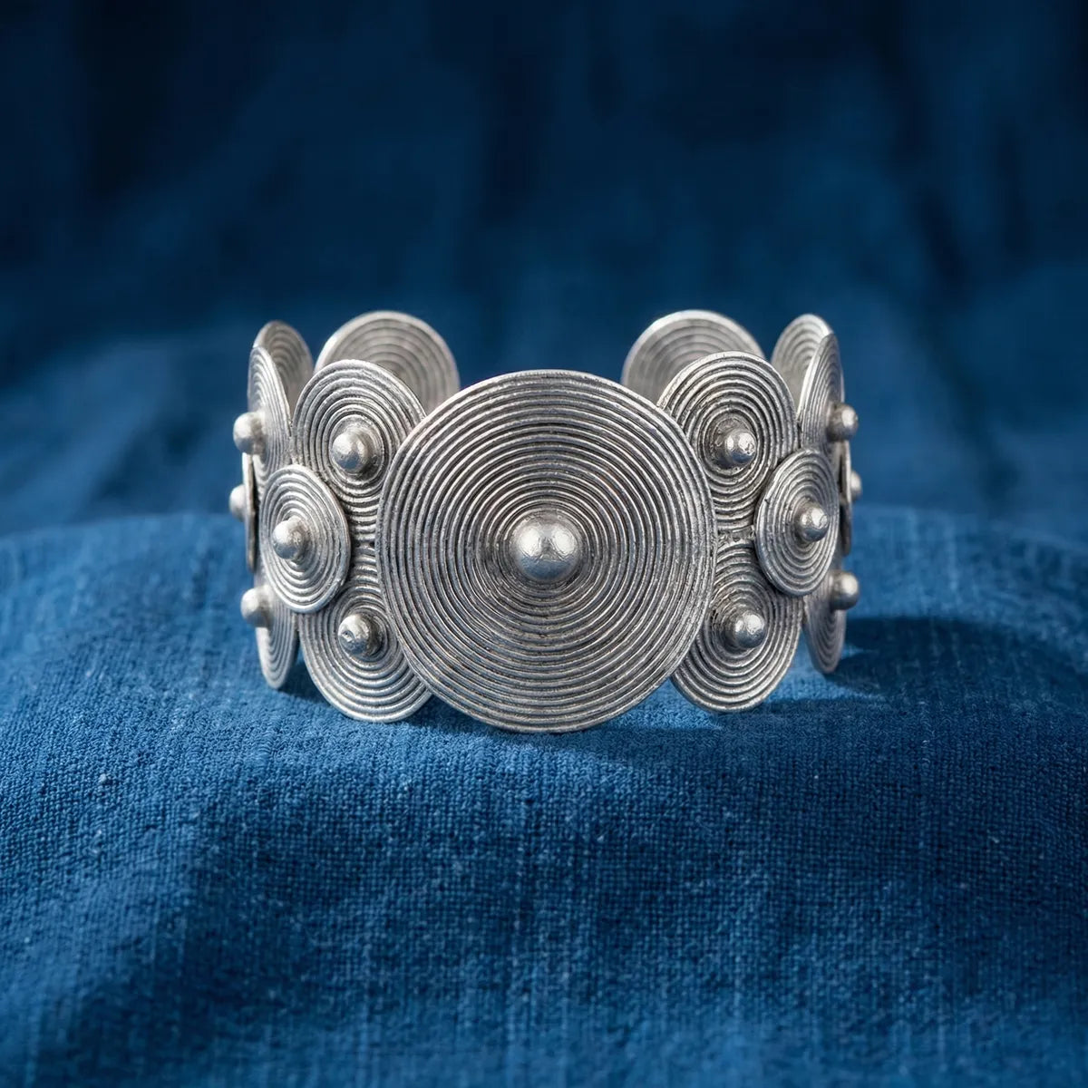 Miao Silver bracelet with circular designs on a blue fabric background