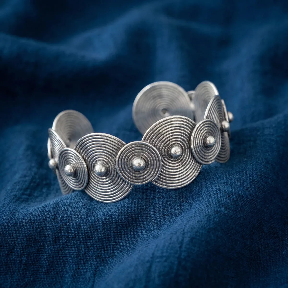 Miao Silver bracelet with circular designs on a blue fabric background